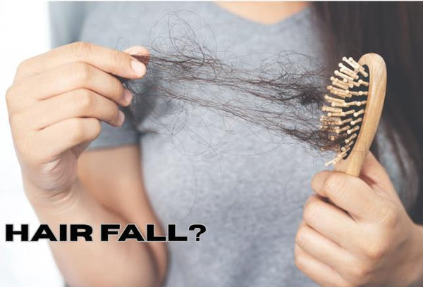 A woman holding a wooden hairbrush filled with loose hair strands alongside the graphic text banner reading HAIR FALL to illustrate hard water breakage symptoms