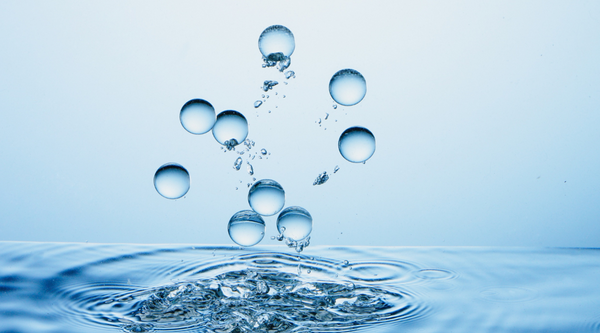 Abstract visual representation of pure clear water bubbles floating upwards from a splashing liquid surface symbolizing mineral filtration and chemical water softening processes