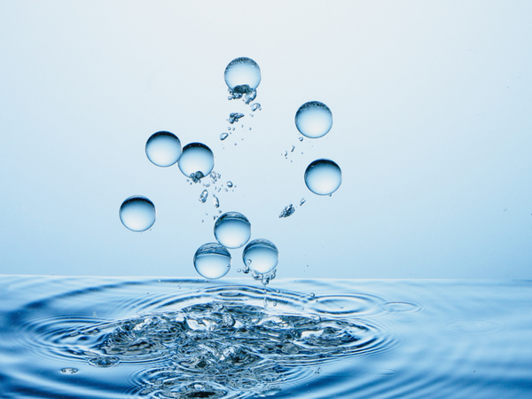 Abstract visual representation of pure clear water bubbles floating upwards from a splashing liquid surface symbolizing mineral filtration and chemical water softening processes