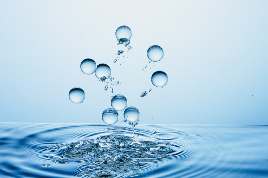 Abstract visual representation of pure clear water bubbles floating upwards from a splashing liquid surface symbolizing mineral filtration and chemical water softening processes